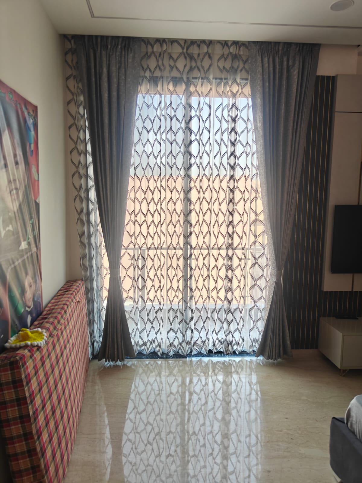 Elegant geometric trellis pattern net sheer curtains paired with grey luxury pleated drapery in a modern living space