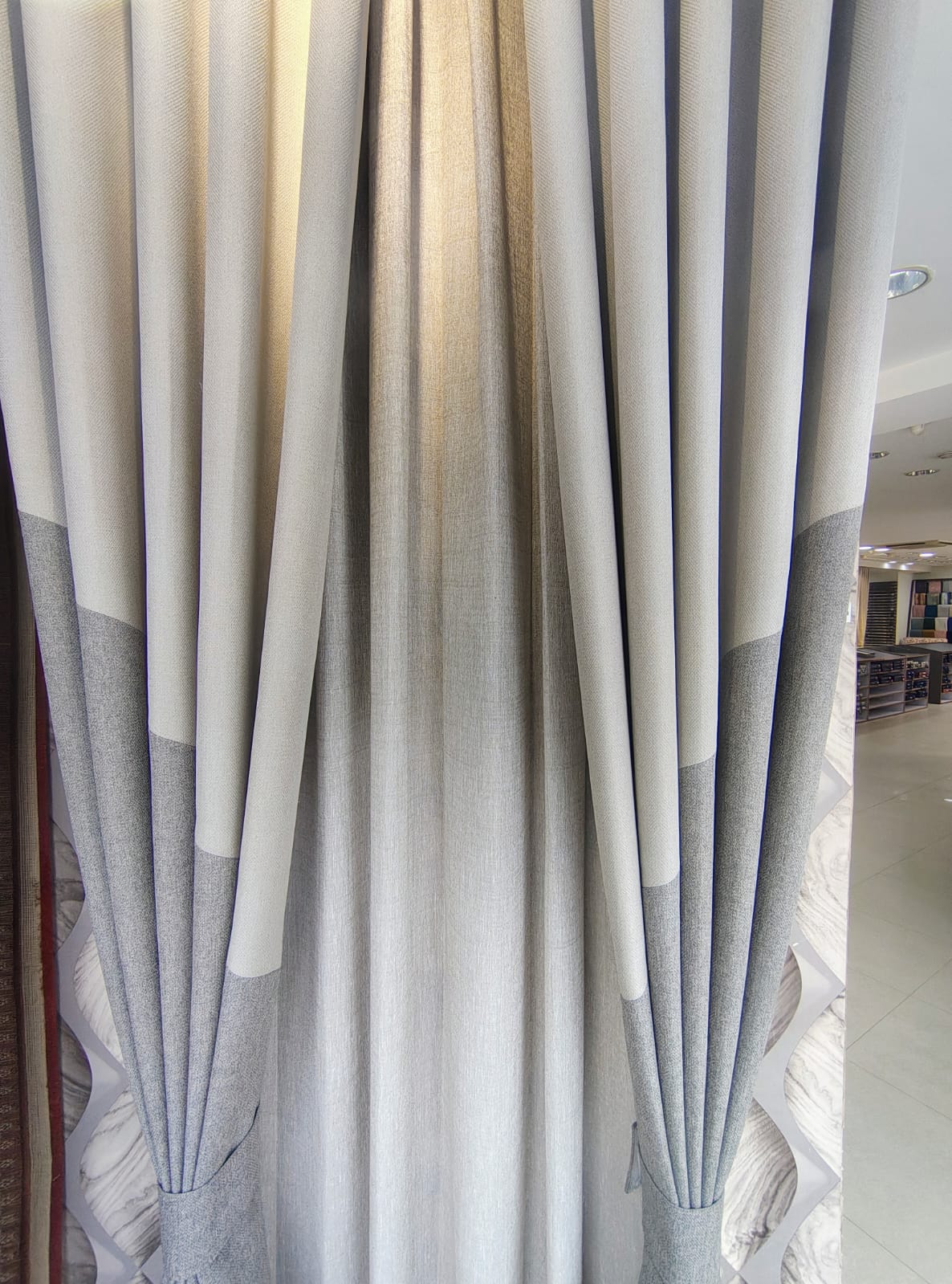 Close-up of a double-color blocked design curtain with clean grey and cream vertical panels on retail display