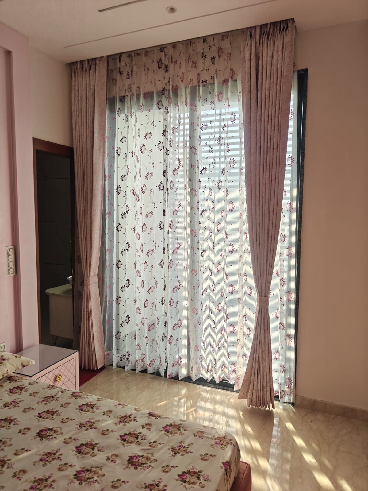 Soft pink custom bedroom drapes featuring a matching sheer curtain with subtle pink floral embroidered patterns