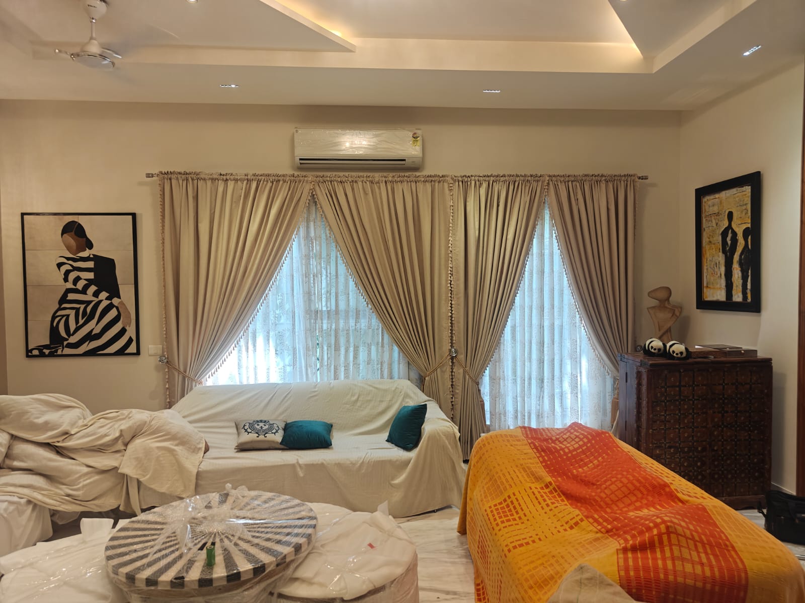 Double window drape installation featuring warm cream drapes with elegant tassel tiebacks and matching sheer curtains