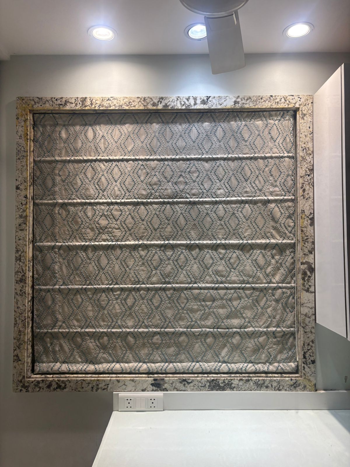 Custom fabric Roman blind featuring a geometric diamond stitched pattern installed inside a premium marble window casing