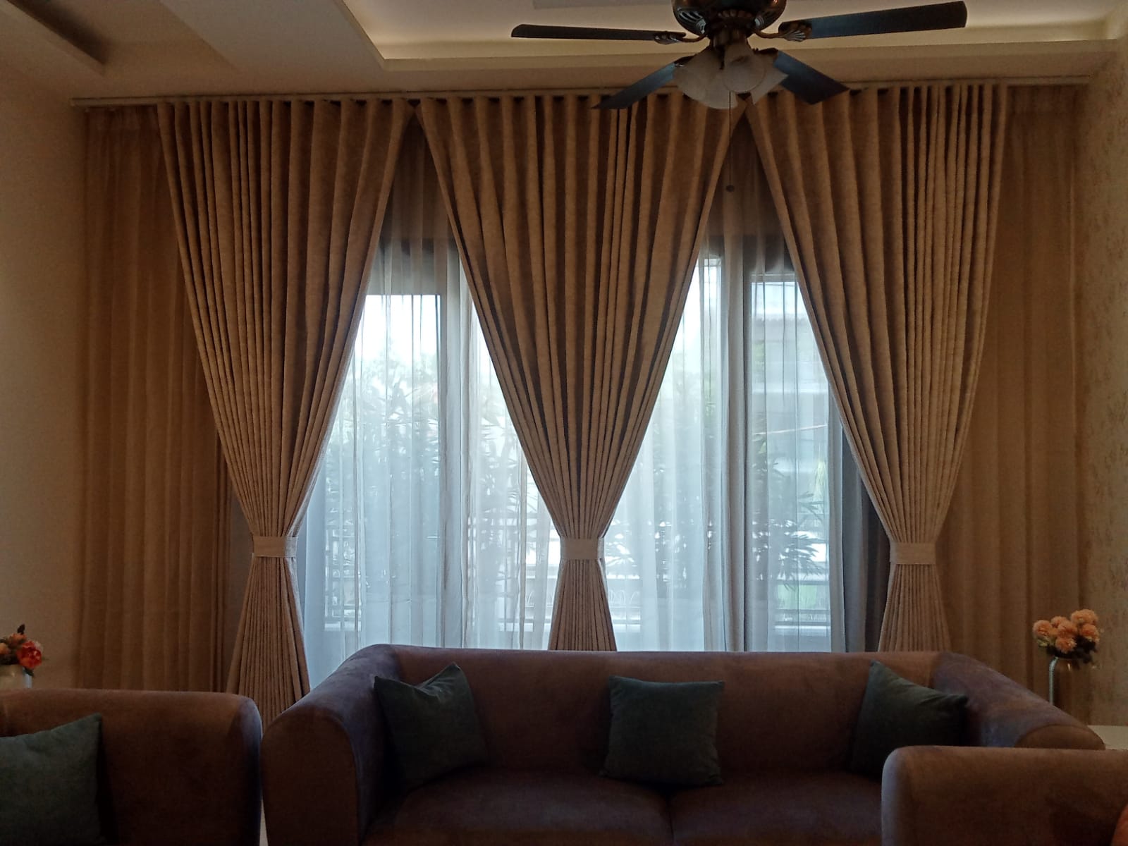 Custom ripple-fold beige pleated living room curtains paired with lightweight white sheer panels on a wide multi-pane window