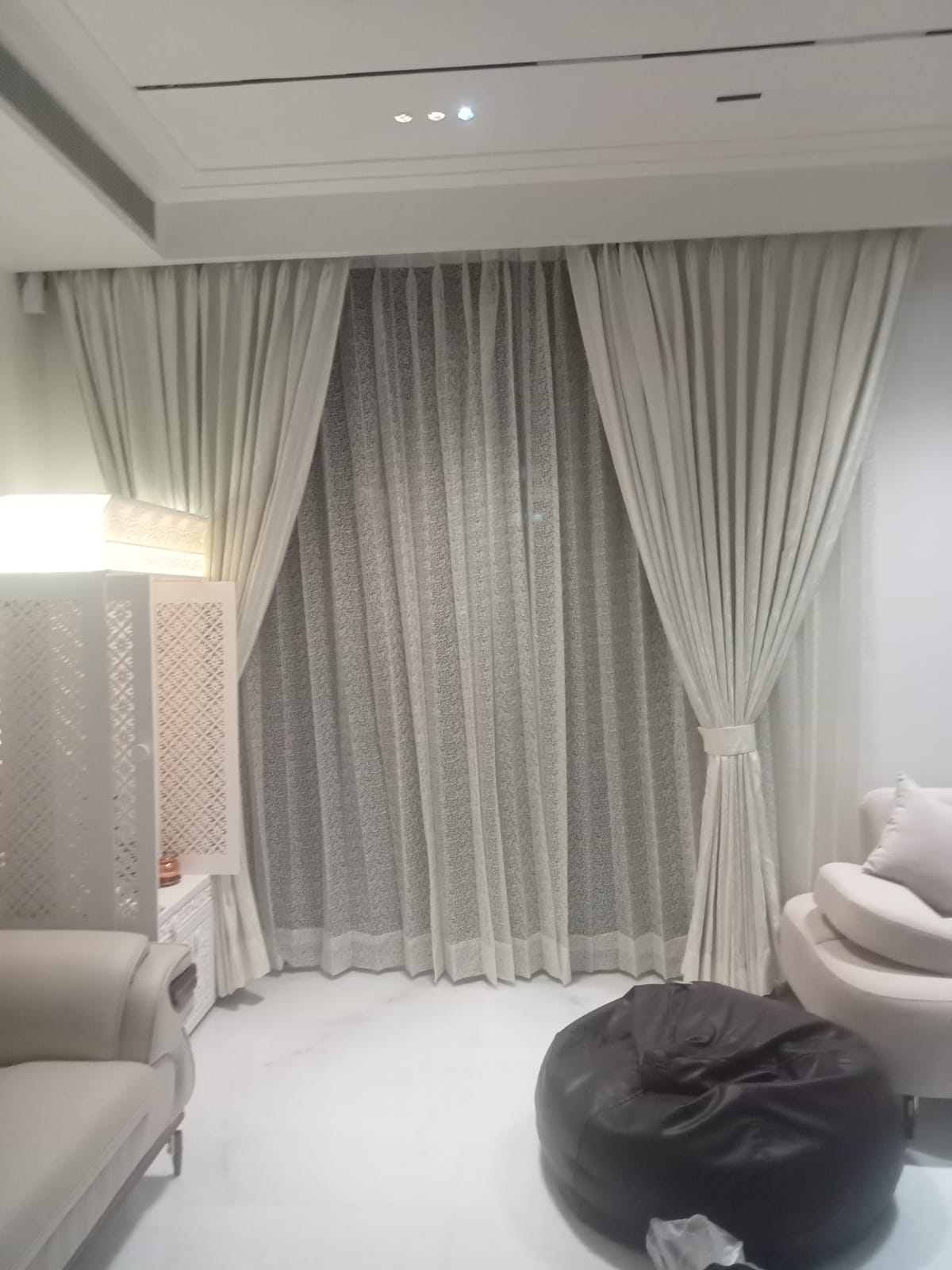 Tailored ivory curtains styled with a grey patterned net sheer curtain in a modern minimalist living room space